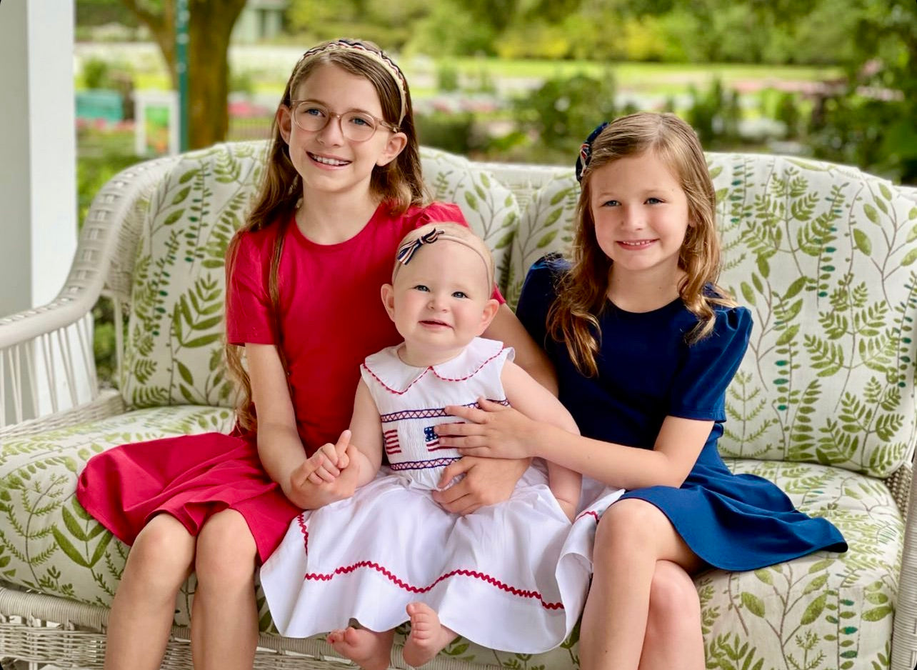 Three girls in cute dresses on a couch.