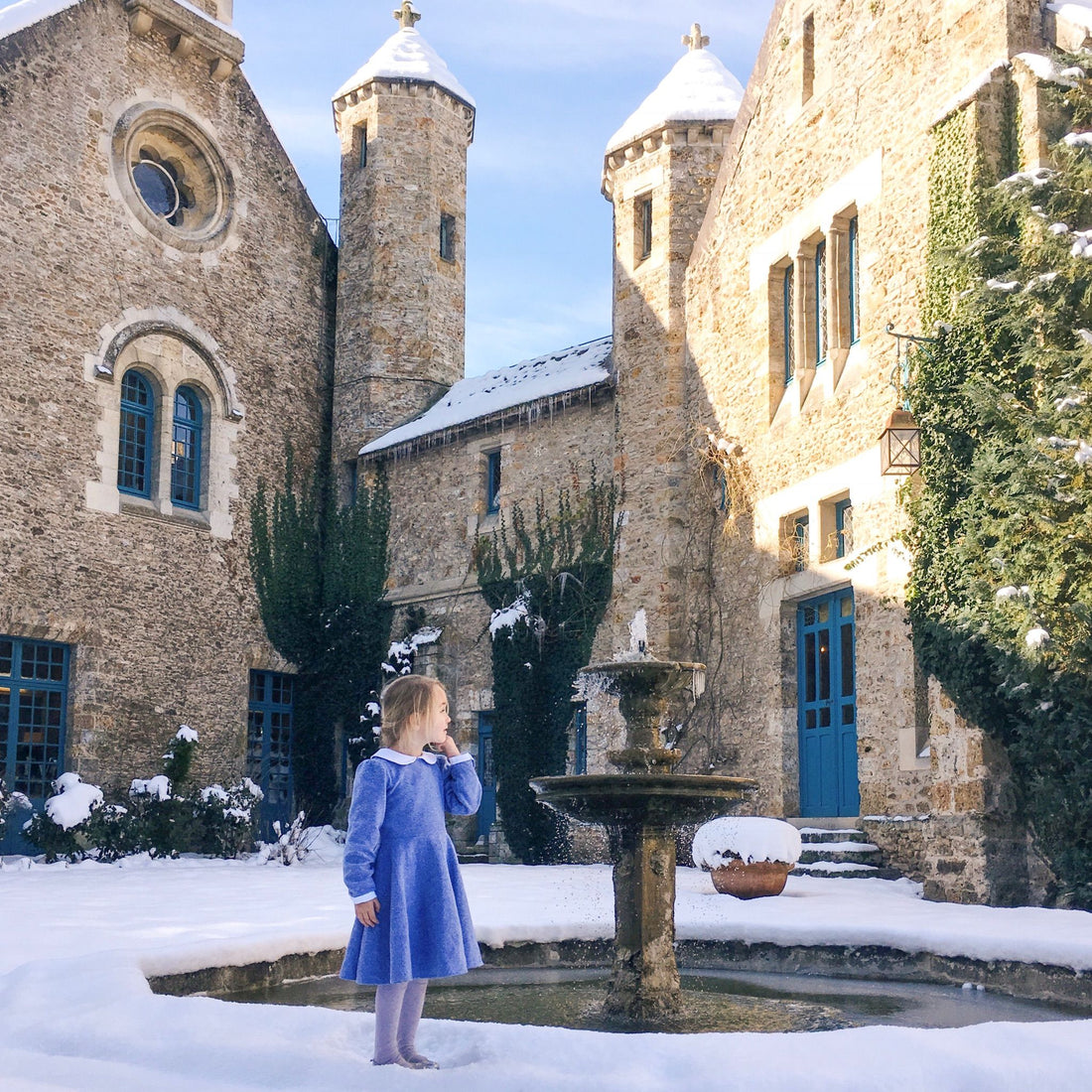 Girl wearing blue flannel dress in the snow at a castle