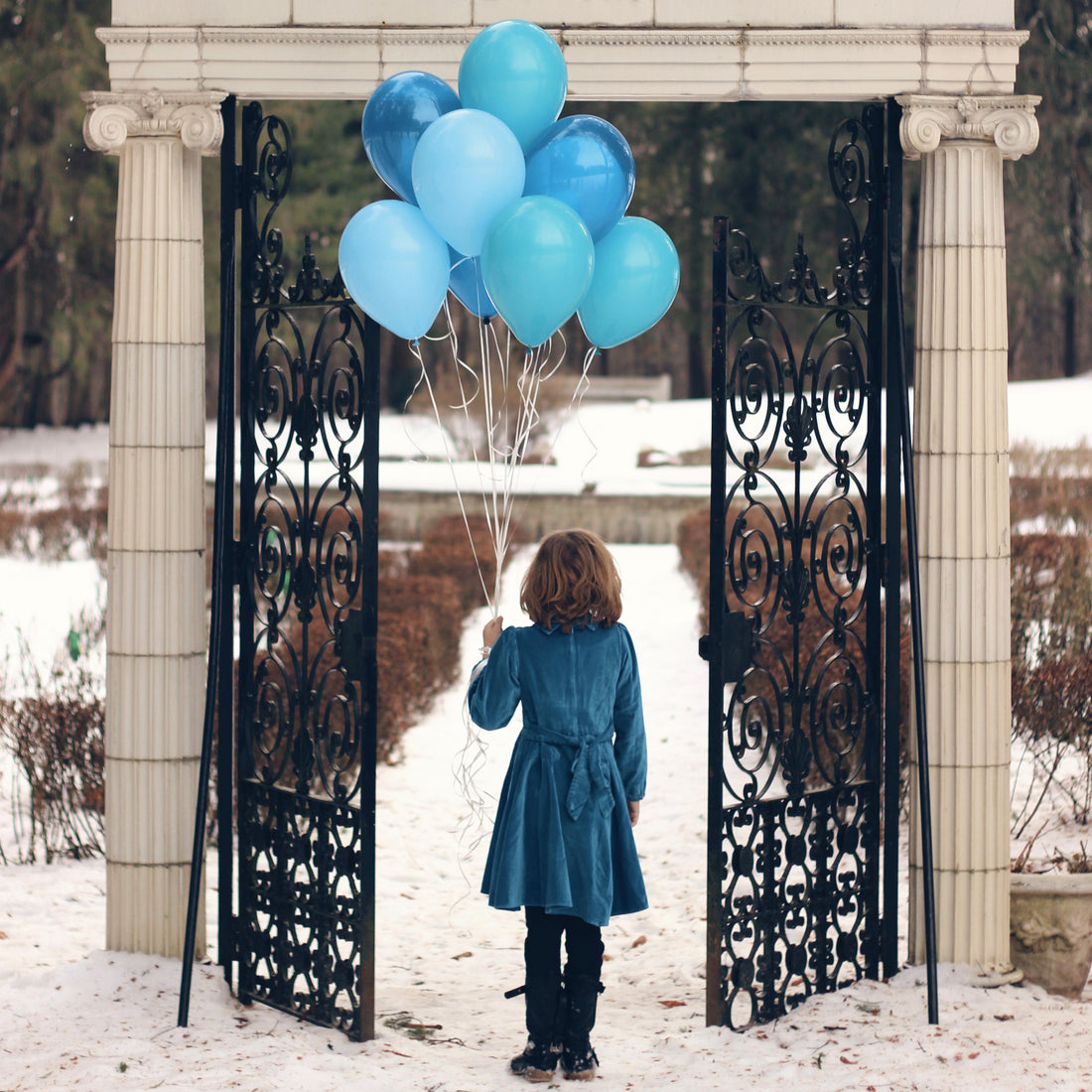 Our blue velvet dress on a girl holding balloons in the snow